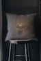 A pillow cover showing a noble stag rendered in shimmering beige against navy blue fabric. Fine beige tan rays extend from the deer's head like sunbeams, with scattered stars.